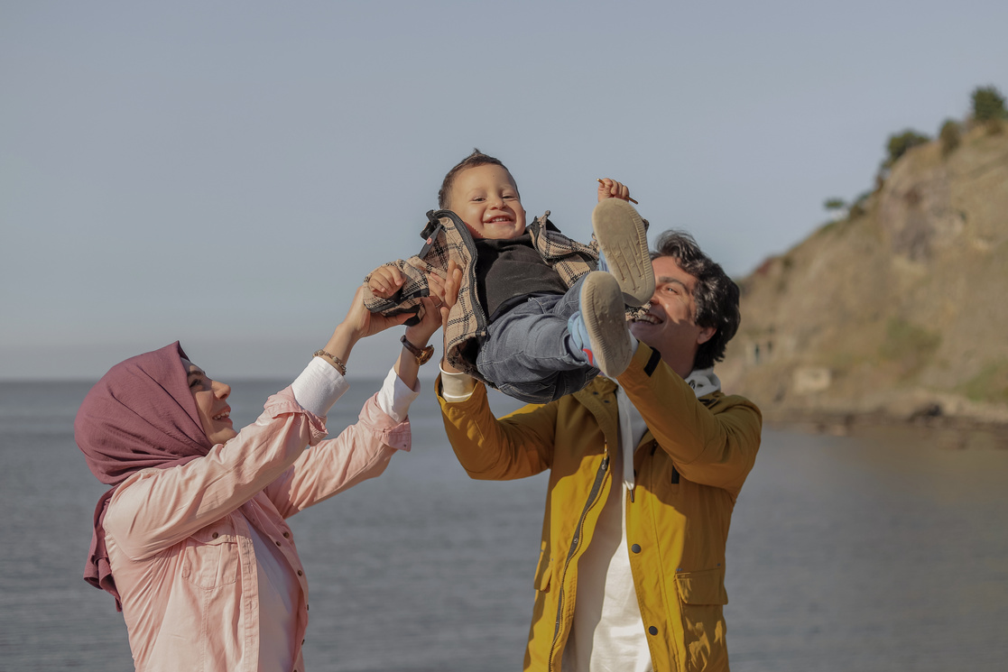 Parents Carrying Their Child by the Sea